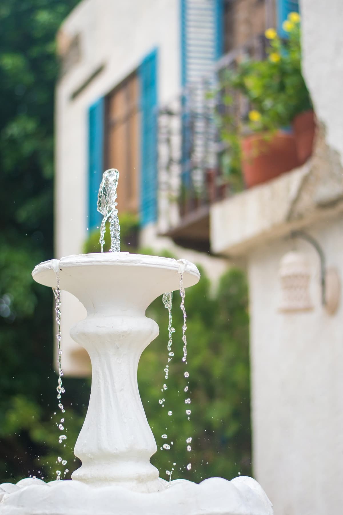 Fuente de agua frente a un balc&oacute;n con persianas azules