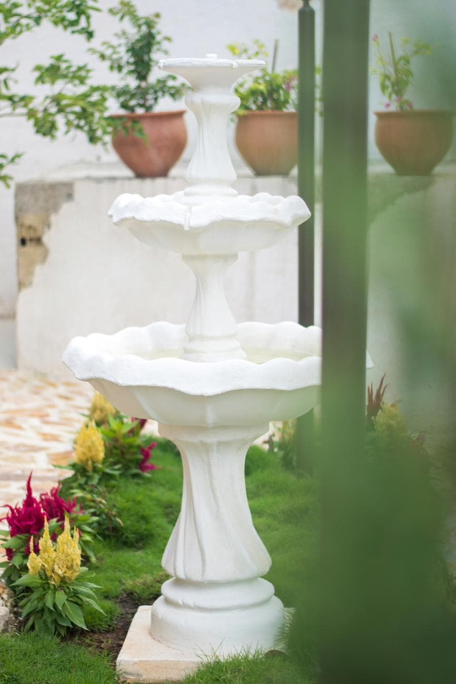 Fuente blanca rodeada de flores en el jardín de Bella Nonna