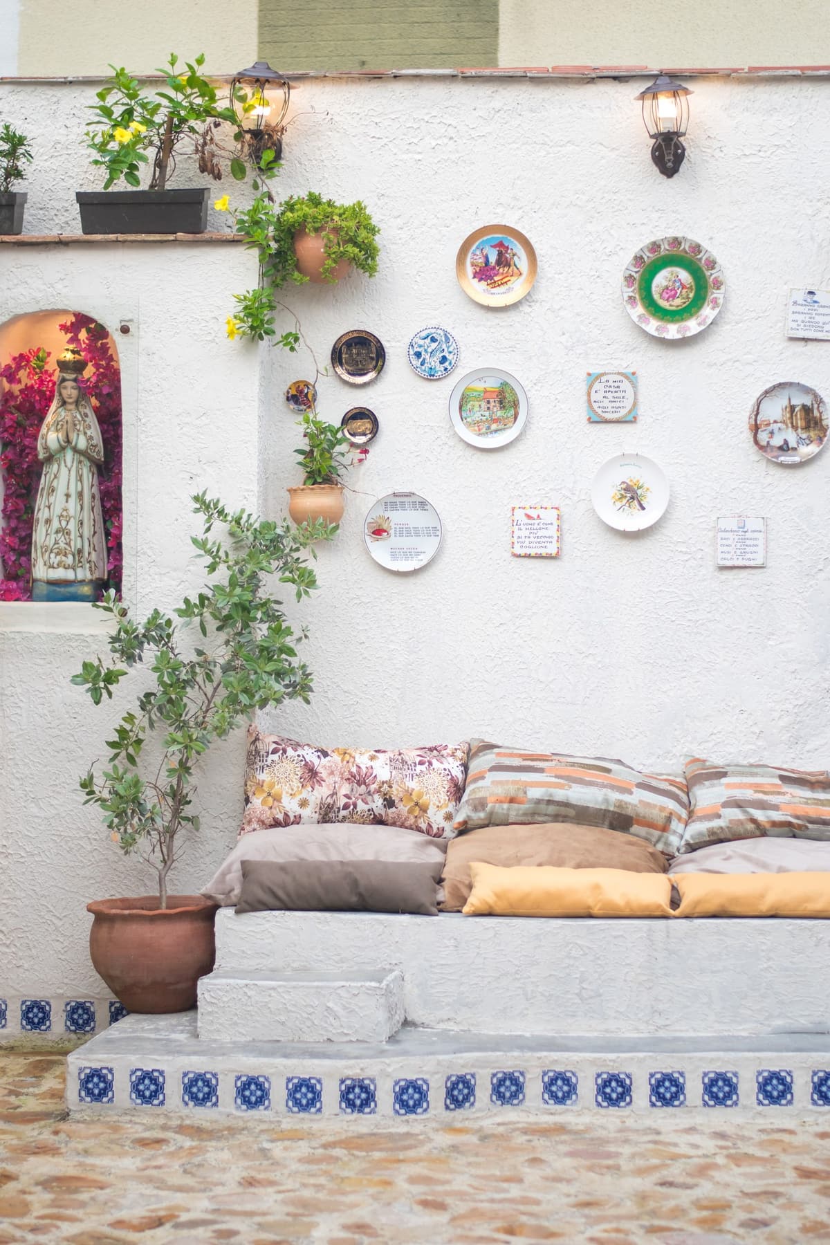 Rinc&oacute;n con banco de cojines, azulejos y platos decorativos en Bella Nonna